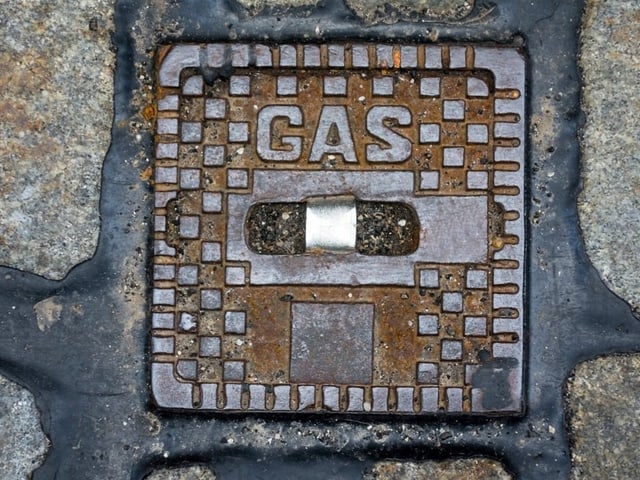 Metallerner Gasdeckel in Pflastersteinen.