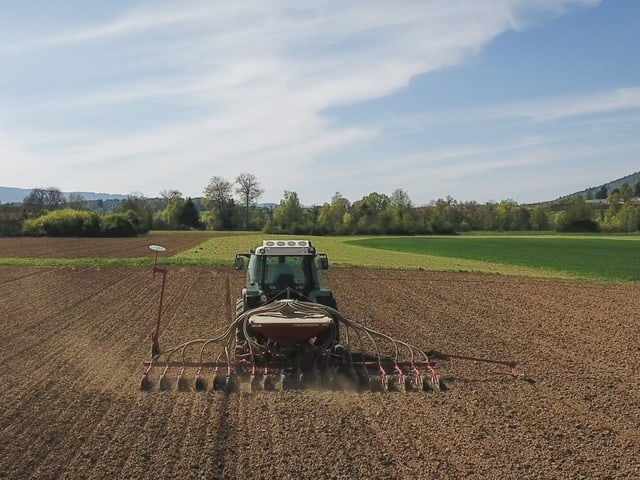 Traktor pflügt Feld unter blauem Himmel.