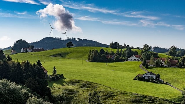 Wiesen und Hügel im Appenzellerland. Im Hintegrund zwei grosse Windräder. 