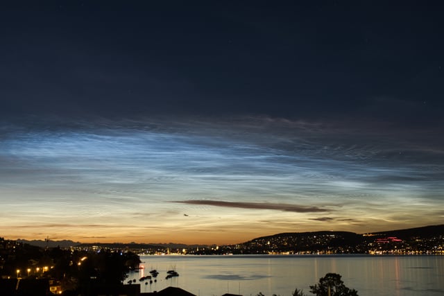 Silbern leuchtende Nachtwolken am dunklen Himmel.