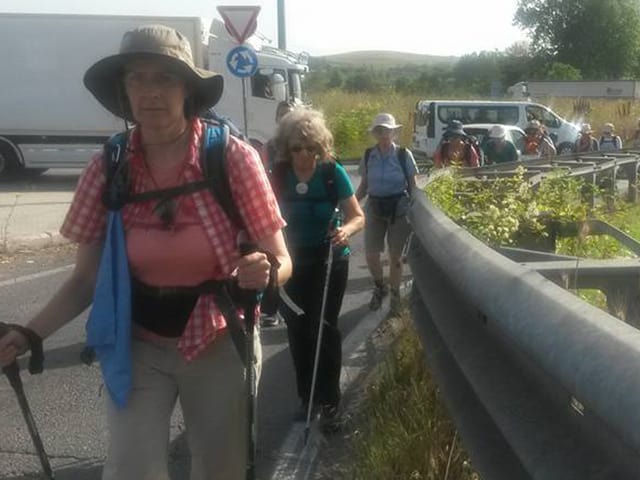 Pilgerinnen laufen neben einer Hauptstrasse. 