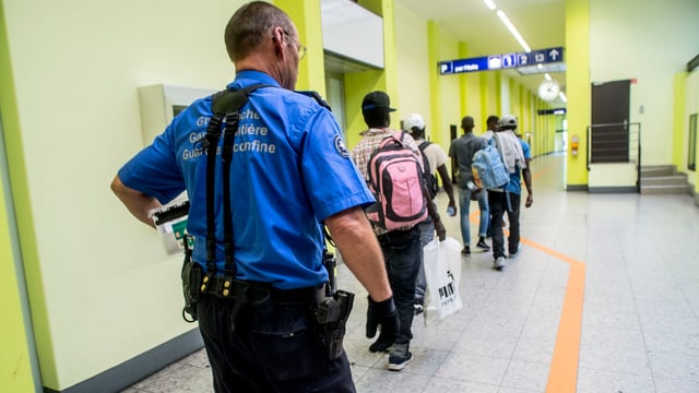 Ein Grenzwächter begleitet am Bahnhof eine Gruppe von Migranten.