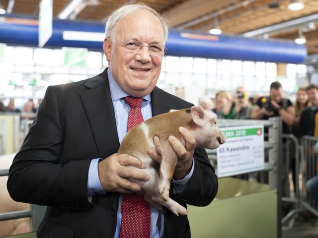 Johann Schneider-Ammann hält ein Ferkel bei einer Messe.