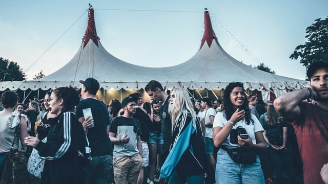 Gruppe von Festival-Gästen vor einem Zelt am Gurtenfestival in Bern.