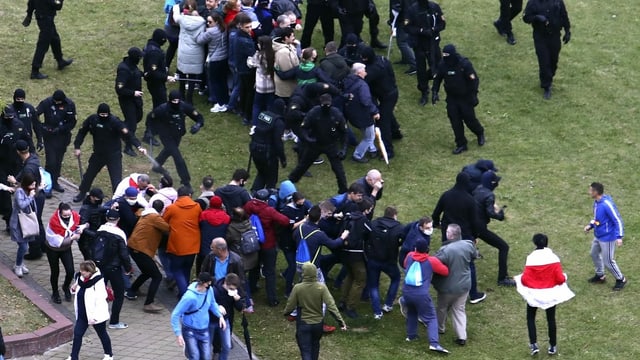 Uniformed policemen beat passersby.