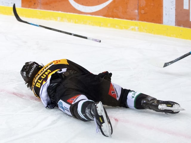 Eishockeyspieler liegt auf dem Eis.