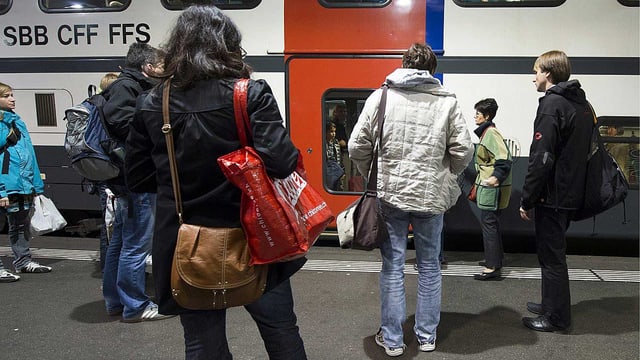 Reisende vor einem Zug der SBB.