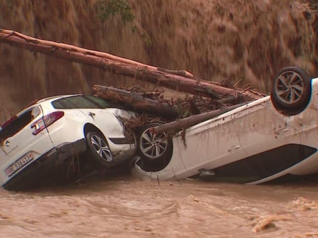 Zwei weisse Autos wurden vom Wasser mitgerissen und schwimmen im Fluss.