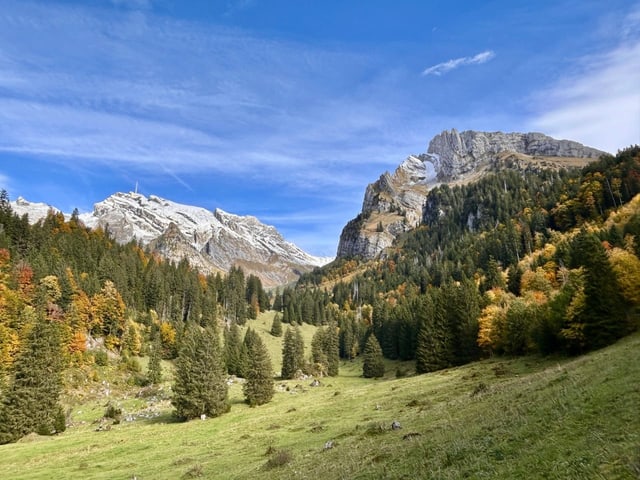 Alpenlandschaft mit schneebedeckten Bergen und Herbstbäumen.