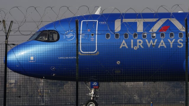 ITA Airways Flugzeug hinter einem Zaun.