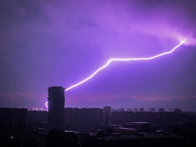 Blitz schlägt in Hochhaus bei Nacht ein.