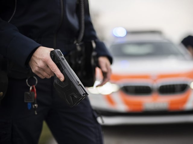 Polizei mit Taser vor Polizeiauto