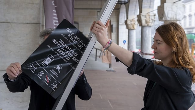 Eine Frau trägt ein Schild davon. 