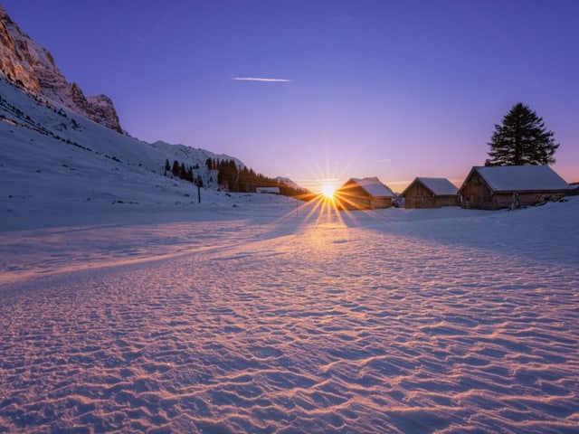 Schneebedeckter Boden, der von Sonne beim Aufgange beschienen wird.