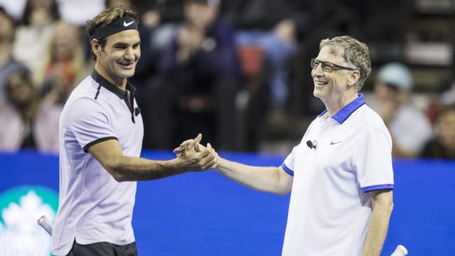 Roger Federer und Bill Gates klatschen auf dem Tennis Platz ab 