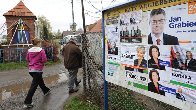 Zwei Personen laufen an Wahlplakaten vorbei