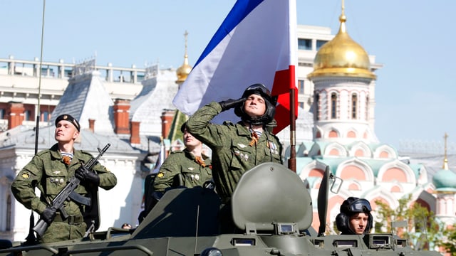 Ein russischer Soldat salutiert an einer Militärparade zum Sieg über Nazideutschland – vor der Krim-Flagge.