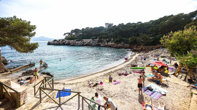 Kleine Sandstrandbucht mit Touristen und Meer