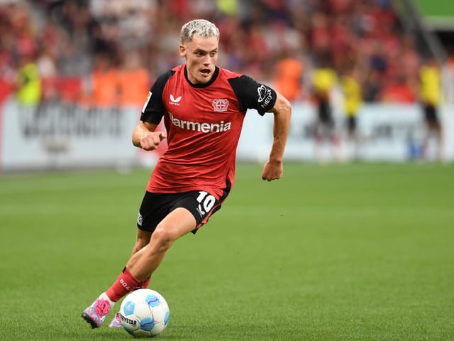 Fussballspieler in rotem Trikot auf dem Spielfeld.