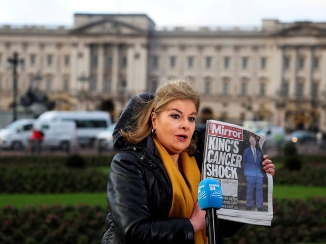 Eine Journalistin hält vor dem Buckingham-Palast eine Zeitung in der Hand. Auf dem Titelblatt steht: «King's Cen