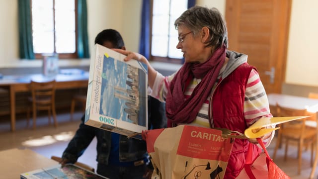  Annemarie Wuerms von Caritas, Mitte, bringt Asylsuchenden Puzzles, aufgenommen am 20. April 2016 in einer temporaeren Asylunterkunft auf der Rigi-Kloesterli. Die Asylsuchende leben waehrend der Zwischensaison in einem von der Caritas als Asylunterkunft genutzten Ferienhaus auf der Rigi-Kloesterli. Zum Zeitpunkt der Fotodokumentation waren 14 von 50 Plaetzen mit Asylsuchenden aus den Laendern Sri Lanka, Afghanistan und Iran besetzt. Die Asylsuchenden lernen Deutsch, verrichten Kuechen-, Haushalts- und Reinigungsarbeiten. In ihrer Freizeit spielen sie beispielweise Volleyball und gewoehnen sich an das Leben in der Schweiz.