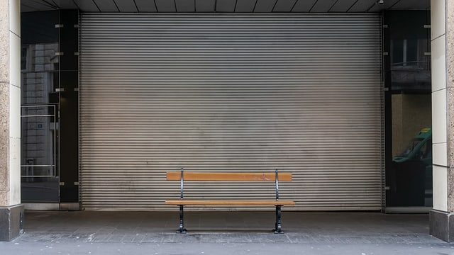 Empty park bench in front of a closed store