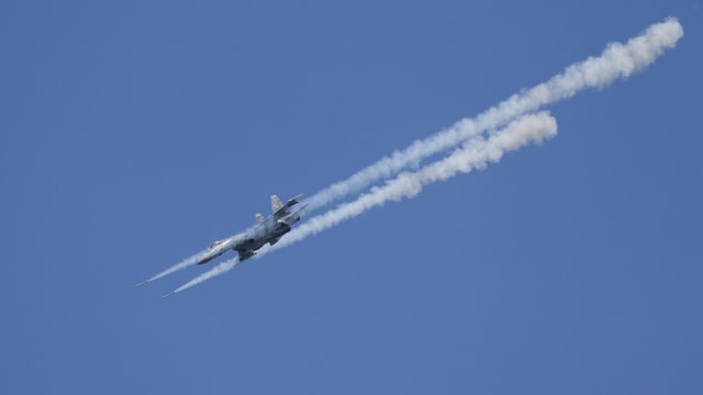 Kampfjet in der Luft, schiesst Raketen ab, Rauchwolken