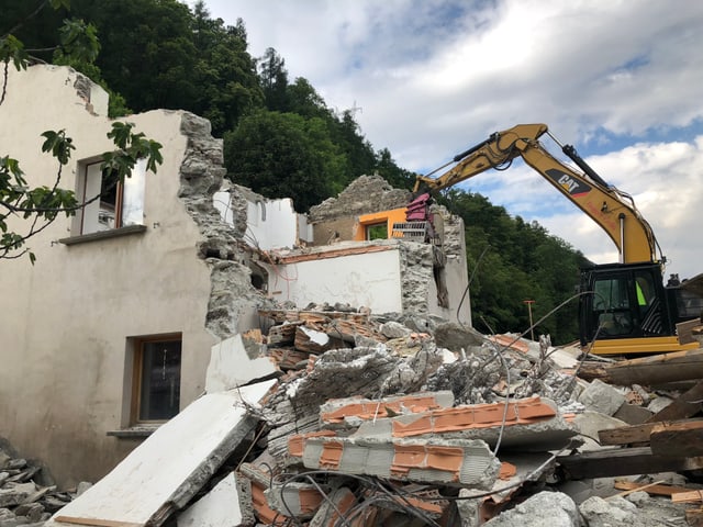 Ein zestörtes Haus und ein Bagger.