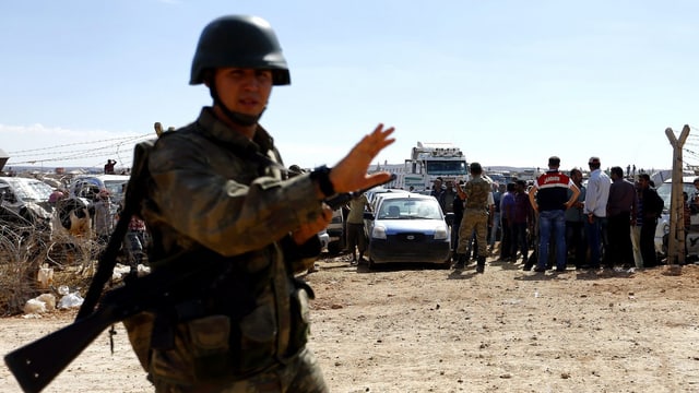 Türkischer Soldat, dahinter Flüchtlinge.