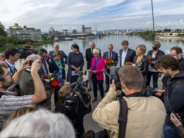 Frau redet und viele Journalistinnen und Journalisten sind um sie herum.