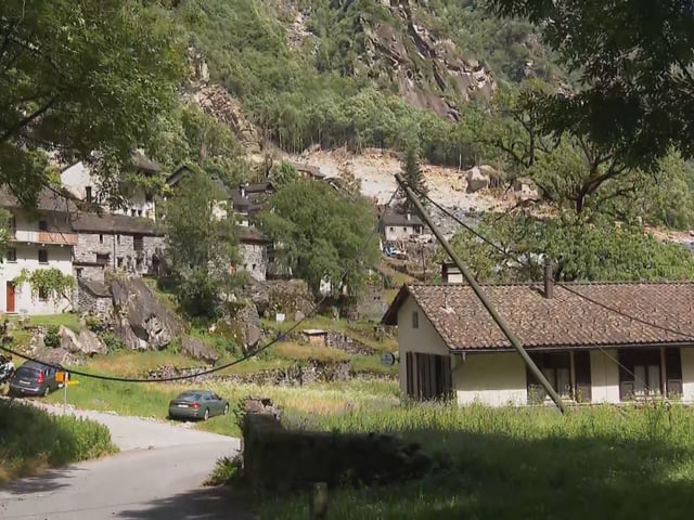 Häuser in Bergdorf mit grüner Landschaft und Strasse.