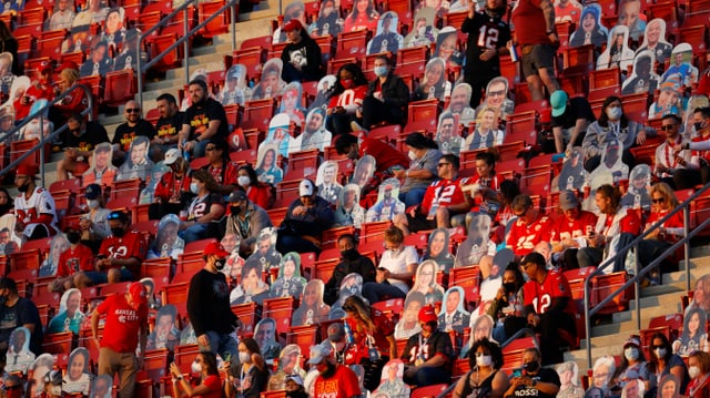 Spectators in the stands with empty individual seats in the middle, some do not wear masks