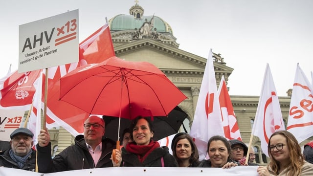 Demonstranten stehen vor dem Bundehaus mit Plakaten in der Hand. 