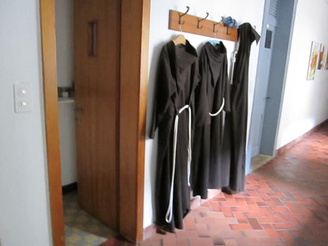 Klostergang mit drei Mönchskutten an der Garderobe.