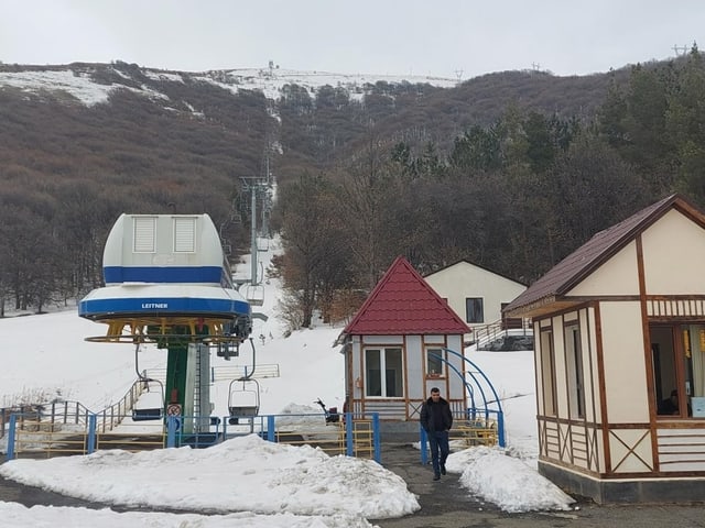 Ein Skilift geht bis zu einem schneebedeckten Hügel etwa 400 Meter höher, daneben zwei kleine Betreiberhäusschen.