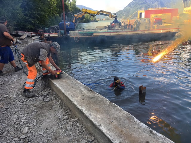 Taucher im Wasser mit brennendem Schweissstab.