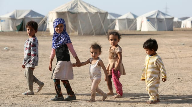 Eine Gruppe von 5 Kindern vor Zelten.