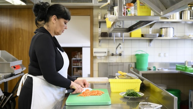 Eine Frau schneidet Gemüse. 