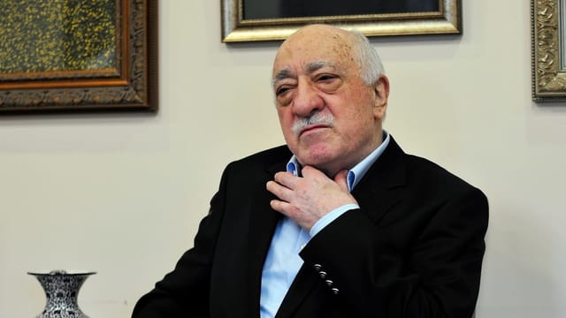 Prediger Gülen fasst sich an den Hemdskragen