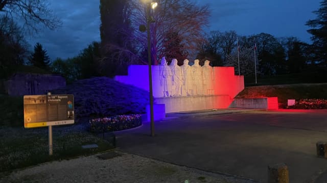 Beleuchtete Betonstatue mit rot-blauer Illumination in der Nacht.