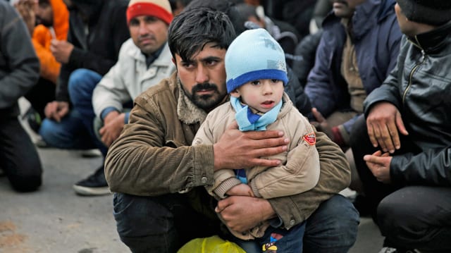 Mehrere Flüchtlinge im Lager in Moria, darunter ein Vater mit seinem kleinen Jungen.