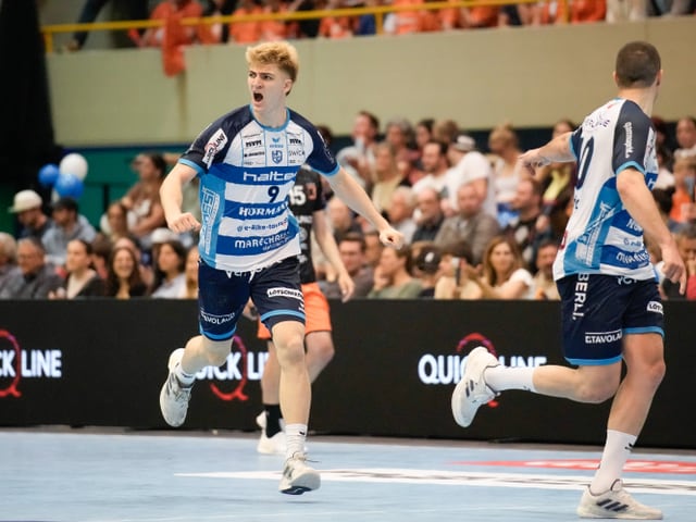 Handballspieler in Jubelpose auf dem Spielfeld.