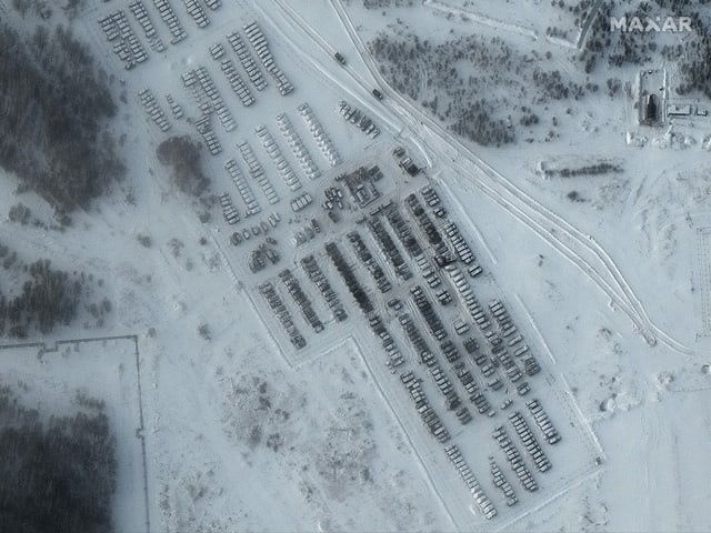 Vogelperspektive: Fahrzeuge stehen in einer Winterlandschaft geparkt. 