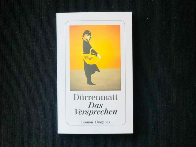 «Das Versprechen. Requiem auf den Kriminalroman» von Friedrich Dürrenmatt liegt auf einem dunklen Sessel