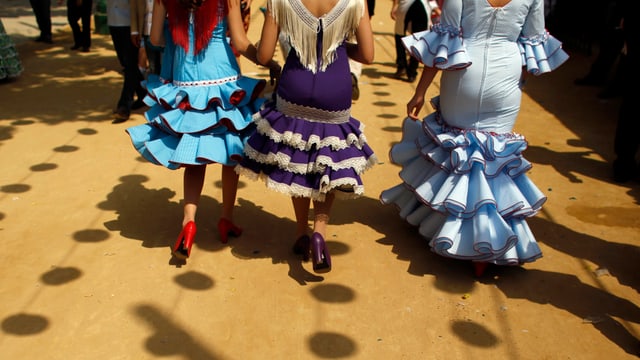 Frauen laufen in wallenden Flamencokleider die Strasse runter