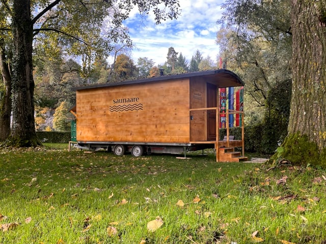 Ein Wagen auf Rädern steht auf einer Wiese. 