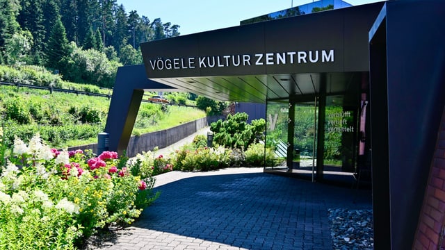 Eingang mit Schriftzug «Vögele Kultur Zentrum». Von Wiesen und Blumen umgeben.