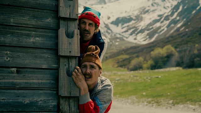 Bax (l.) und Juni schauen mit bangem Blick hinter einer Berghütte hervor.