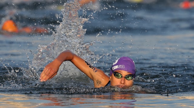 Eine Schwimerin schwing ihren rechten Arm aus dem Wasser