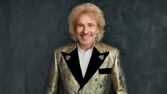 Thomas Gottschalk steht vor einem schwarzen Hintergrund